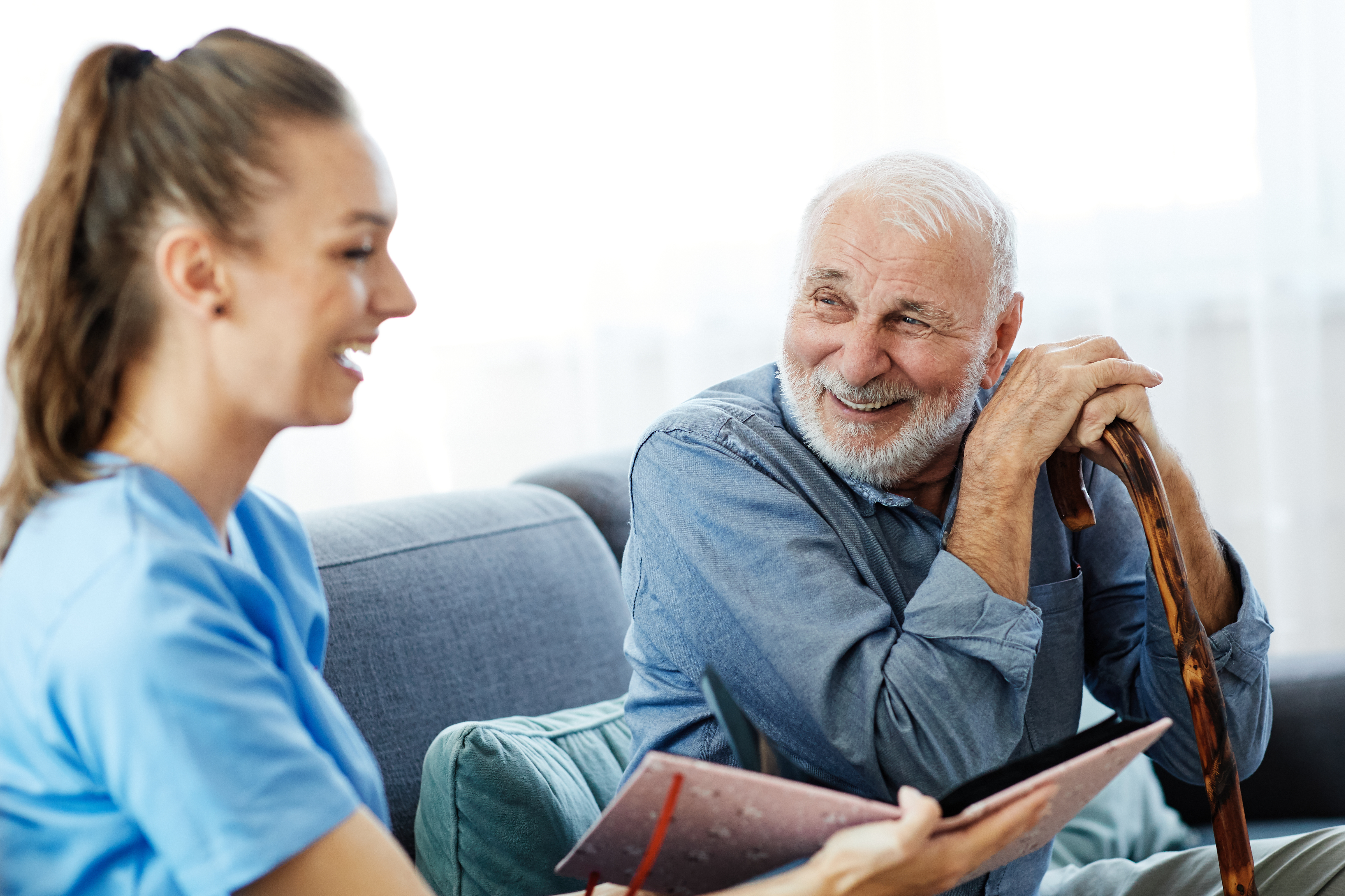 Doctor or nurse caregiver showing a brochure to  senior man at home or nursing home