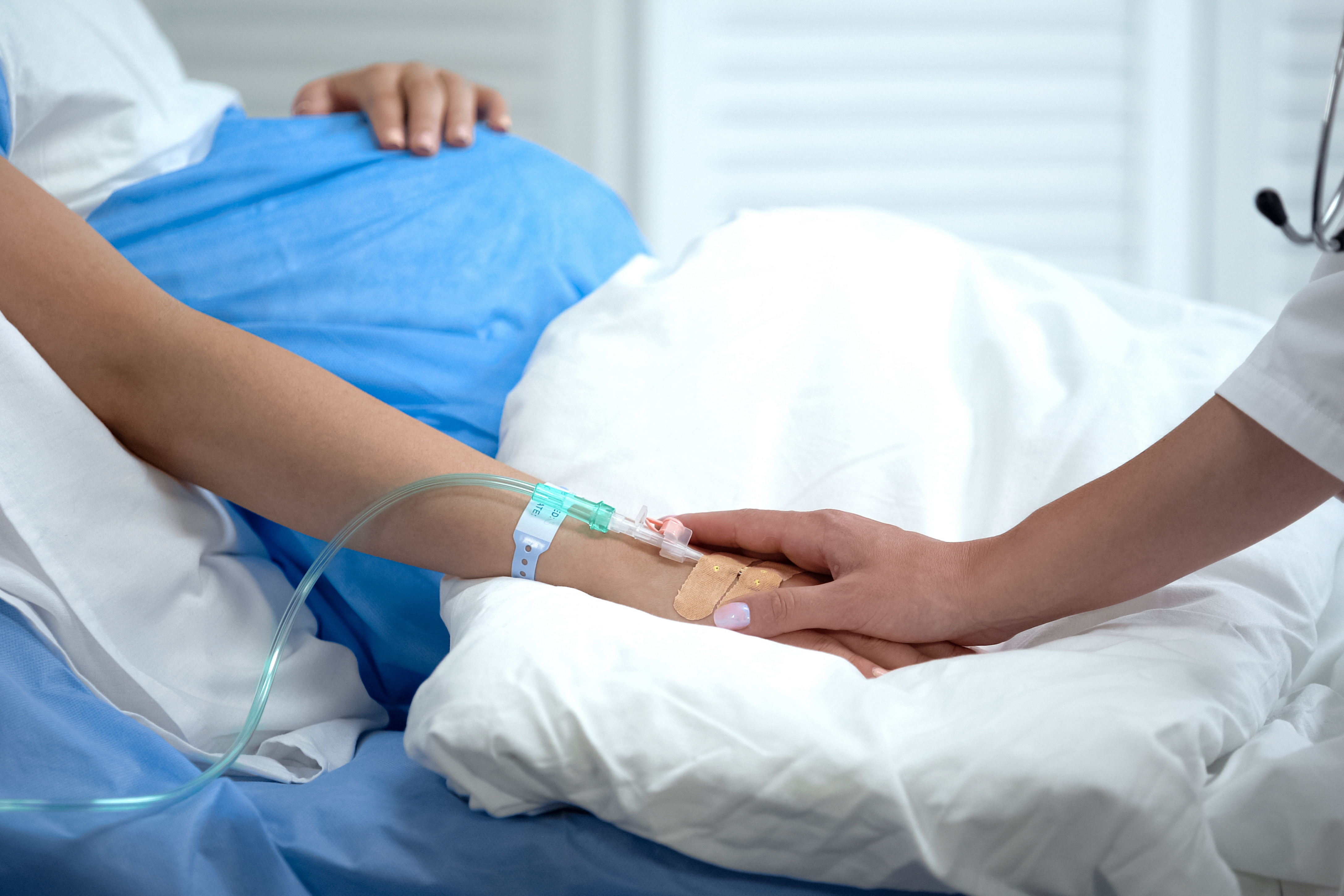 Doctor holding pregnant woman hand with catheter, birth defects prevention